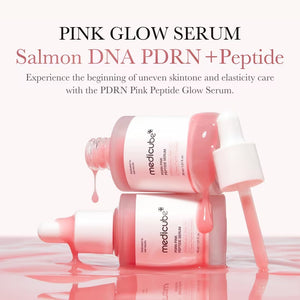 A pink dropper bottle of KOSMIC KBEAUTY SKINCARE MEDICUBE - PDRN PINK PEPTIDE SERUM, 30G is featured alongside large and small pink serum droplets in the background. The label emphasizes a peptide complex and PDRN/sodium DNA, making this glow serum an essential choice for a radiant complexion.