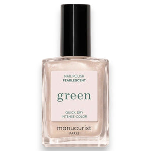 Wearing a black satin top, a person holds a bottle of MANUCURIST - GREEN™ NAIL POLISH IN PEARLESCENT by MANUCURIST INC, displaying their neatly manicured nails.