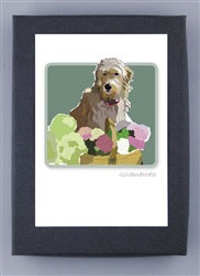 PAPER RUSSELLS - GOLDENDOODLE BOXED CARDS by PAPER RUSSELLS feature a Goldendoodle behind a basket of colorful flowers on a muted green background, printed on recycled paper and made in the USA.