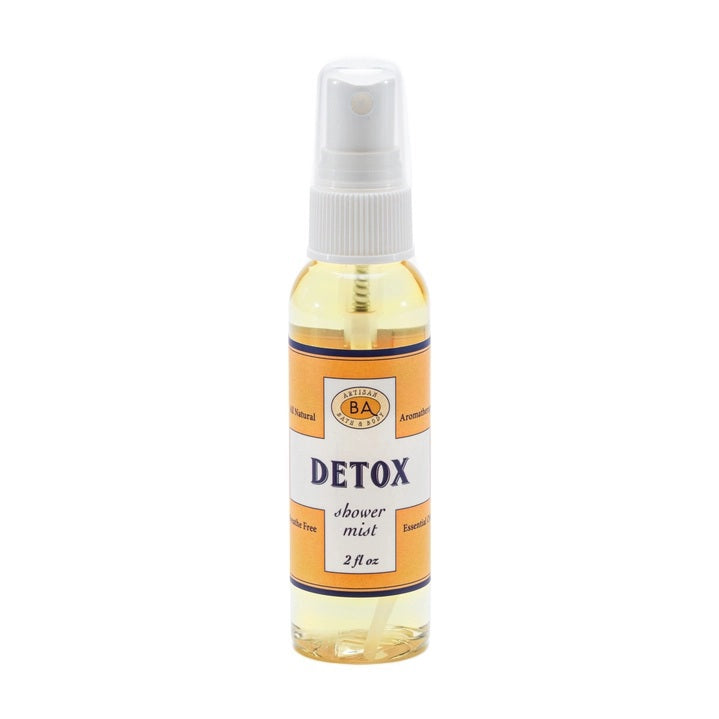 Six small bottles labeled Breathe, Boost, Unwind, Sleep, Detox, and Recover—each filled with essential oil shower mists like uplifting lemon and ginger—are arranged on white shelves in a tiled shower niche with a geometric gray and white pattern. Create your own aromatherapy steam room right at home.