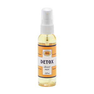 Six small bottles labeled Breathe, Boost, Unwind, Sleep, Detox, and Recover—each filled with essential oil shower mists like uplifting lemon and ginger—are arranged on white shelves in a tiled shower niche with a geometric gray and white pattern. Create your own aromatherapy steam room right at home.