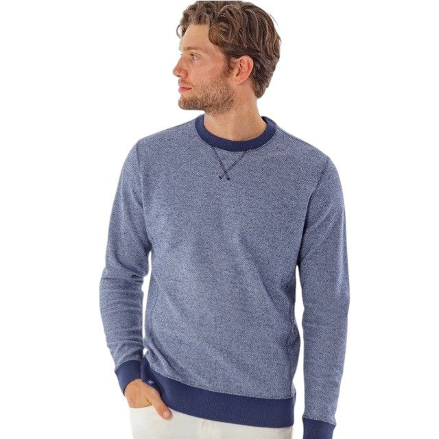 A man with short brown hair wearing the CRIQUET - French Terry Crewneck Sweatshirt in Dusty Blue and white pants stands with one hand in his pocket, looking to his left against a white background.
