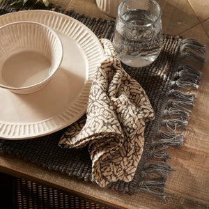 The NAPA HOME AND GARDEN - PIA napkin, crafted from hand-dyed acrylic wool, features a black and white geometric pattern with interlocking shapes for a contemporary and cozy look.