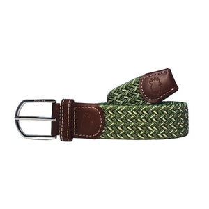 The ROOSTAS - REMINGTON WOVEN STRETCH BELT features a green herringbone weave, brown leather accents with embossed logo, decorative stitching, and a silver buckle. Adjustable for comfort and style on any occasion.