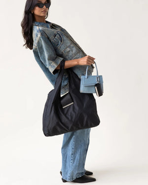 The KEOTE - KEYCHAIN TOTE IN JET BLACK by KEOTE is a reusable black tote made of crinkled fabric, shown flat with a matching small carrying case—ideal as a compact bag for easy storage and daily use.