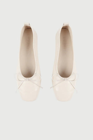 The Augusta - Sienna Ballet Flat by AUGUSTA is a single silver-colored shoe featuring a subtle metallic sheen and a simple bow on the front. It has a low brown sole and a pull tab at the back. Handcrafted in Spain from leather, this ballet flat is shown from the side against a light gray background.