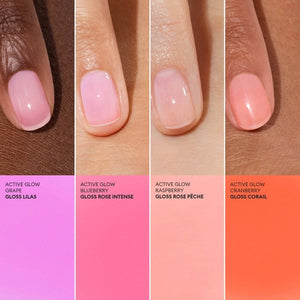 A pink serum drop labeled with its ingredients: raspberry extract (strengthens nails), AHAs (restore and harden), and sweet almond oil (nourishes). The text highlights that MANUCURIST - ACTIVE GLOW CARE POLISH by MANUCURIST INC is 85.5% plant-based—making it the ideal nail strengthener for achieving healthy, glass-like nails.