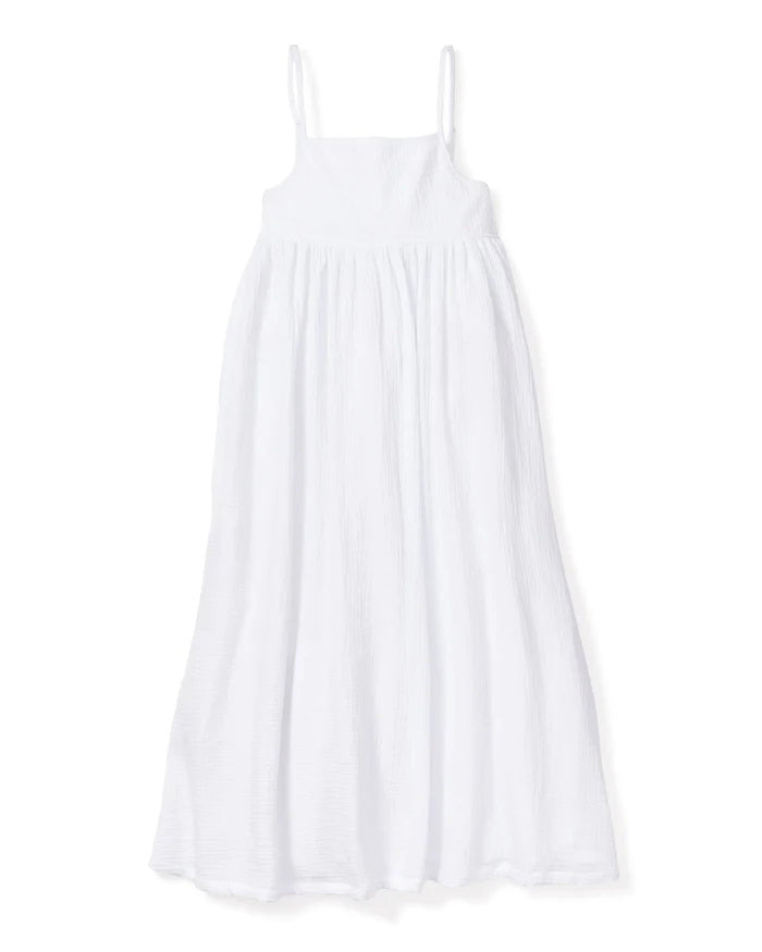 The PETITE PLUME - GAUZE SERENE NIGHT DRESS by PETITE PLUME is a flowing, sleeveless, white cotton gauze sundress with thin spaghetti straps. It features a fitted bodice and a long, airy skirt that reaches down to the ankles, creating an elegant and breezy look ideal for luxury loungewear.