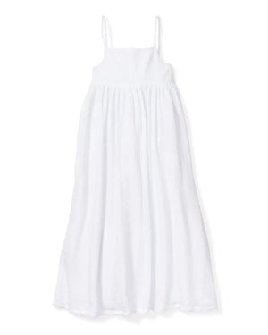 The PETITE PLUME - GAUZE SERENE NIGHT DRESS by PETITE PLUME is a flowing, sleeveless, white cotton gauze sundress with thin spaghetti straps. It features a fitted bodice and a long, airy skirt that reaches down to the ankles, creating an elegant and breezy look ideal for luxury loungewear.
