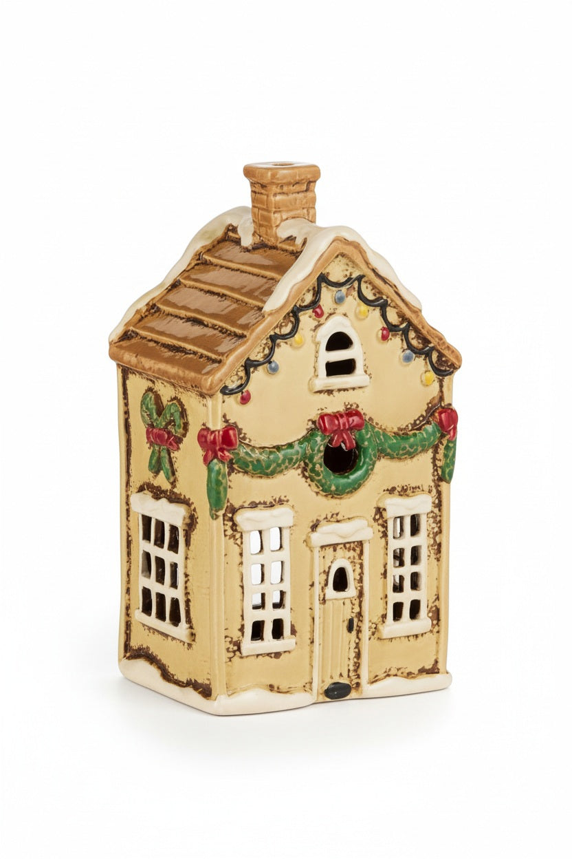 TAN CERAMIC HOUSE 8″ holiday figurine decorated with garlands, wreaths, and string lights, serving as a festive clay candle holder.