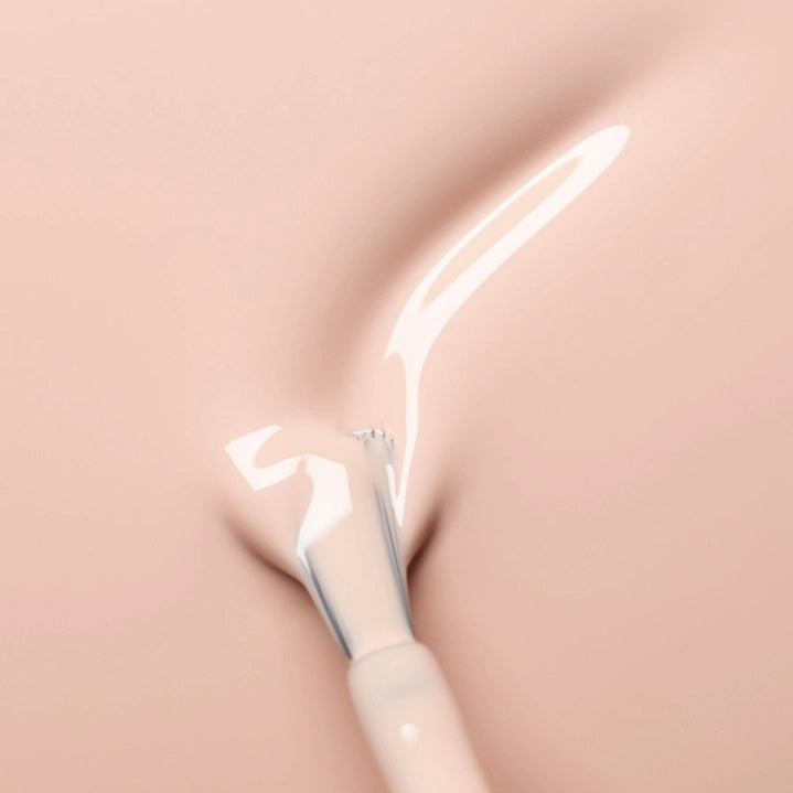 A hand with neatly manicured nails—polished with MANUCURIST - GREEN™ Nail Polish in Pastel Pink by MANUCURIST INC—rests on light brown sand, a few grains clinging to the skin.
