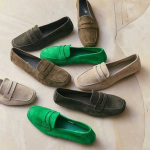 A person stands on a light floor wearing blue jeans and REQINS - HEMA SUEDE LOAFER IN GAZON GREEN by REQINS, featuring a leather insole.