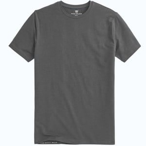 A man with short dark hair and a beard wears a MACK WELDON SILVER CREW NECK T-SHIRT and a black watch, standing against a light gray background with a neutral expression.