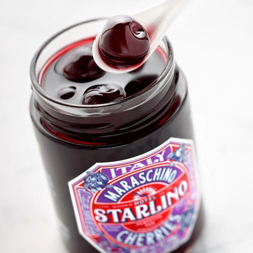 A jar of STARLINO ITALIAN MARASCHINO CHERRIES from the HOTEL STARLINO ITALIAN MARASCHINO brand features a vibrant red label adorned with intricate designs and proudly declares its Italian origin. Weighing 14.1 oz (400g), these luxury Maraschino cherries make an exquisite cocktail garnish.