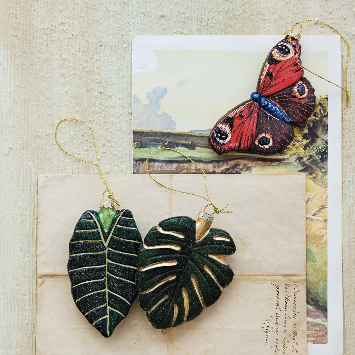 A Creative Coop hand-painted mercury glass butterfly ornament with glitter, featuring orange and brown wings with eye-spot patterns.
