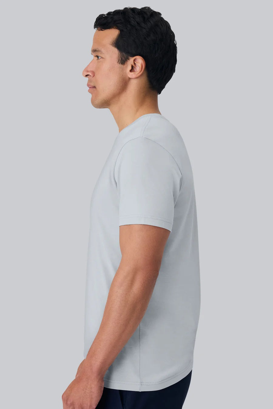 A man with short dark hair wears the MACK WELDON Pima Crew Neck T-Shirt in Steam and dark pants, standing against a plain light gray background and looking at the camera with a neutral expression.