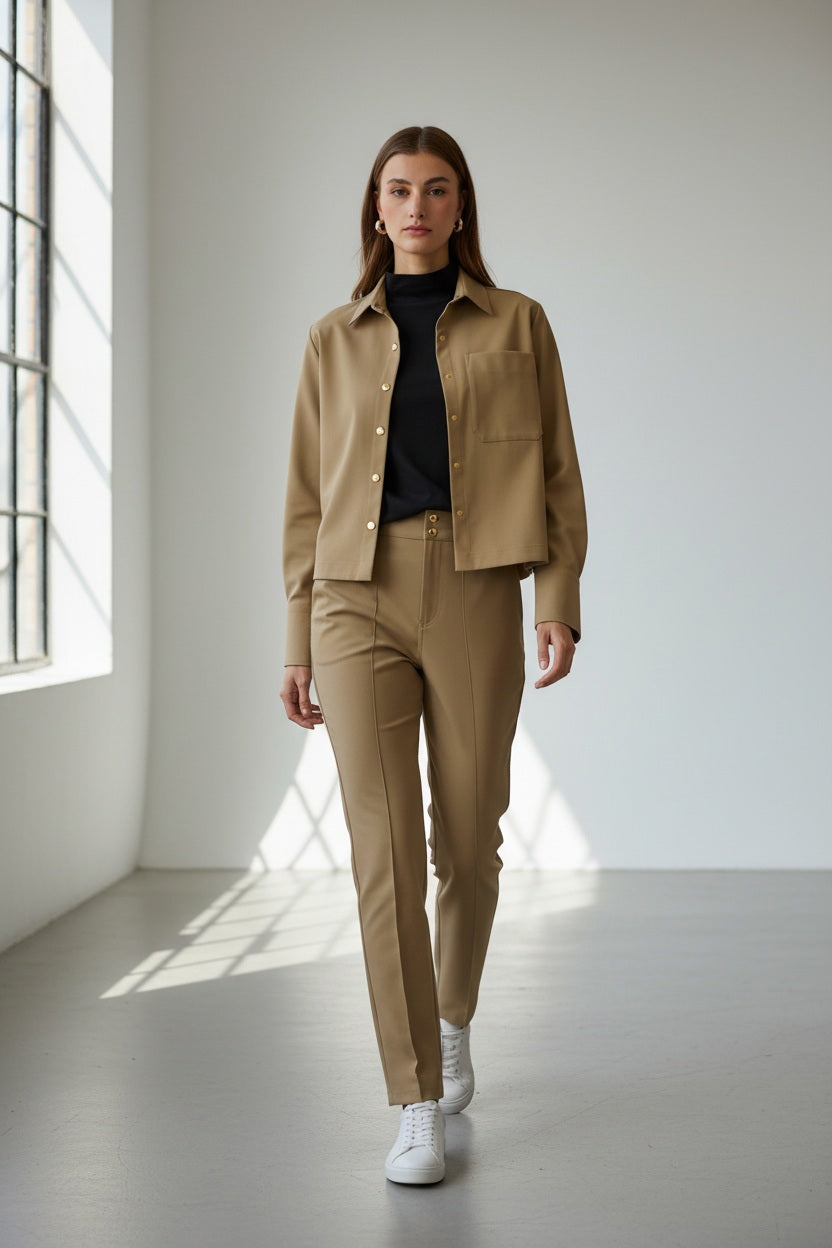 A woman with straight brown hair and gold hoop earrings is seen from the back in the HINSON WU ASTRID Long Sleeve Traveler's Twill Shirt Jacket, styled for travel, against a plain background.