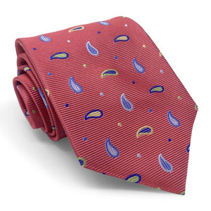 A rolled-up BIRD DOG BAY PETER-BLAIR Bespoke Paisley Soiree Silk Tie in red, featuring blue, yellow, and green paisleys and dots with a subtle diagonal ribbed texture, expertly handmade in New York.