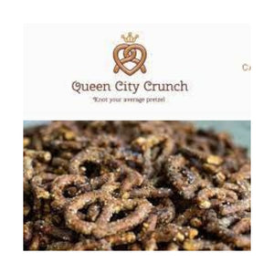 A white and brown bag of QUEEN CITY CRUNCH - OG features a gold heart-shaped pretzel with a crown and the phrases "Knot Your Average Pretzel" and "The OG, savory with a kick." Brand: QUEEN CITY CRUNCH.
