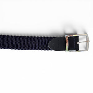 A close-up of the ATHISON reversible stretch belt featuring indigo, manatee, and light blue stripes reversing to solid indigo, with a textured finish and a silver rectangular buckle on a white background.