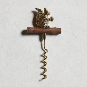 The BE HOME - SQUIRREL CORKSCREW by BE HOME, INC features a brown branch handle and a metallic squirrel with an acorn, adding woodland charm to your bar—perfect as a unique hostess gift. Shown on a light textured background.