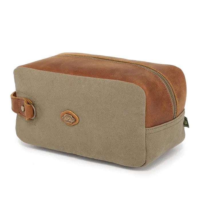 The TSD BRAND Valley Oak Toiletry Bag in olive is a rectangular, handcrafted travel essential made from durable canvas, featuring a tan leather strap and a small leather patch for added style.