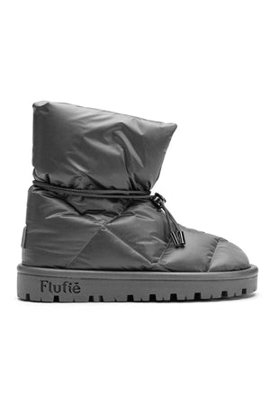 The METALLIC PILLOW BOOT by FLUFIE is a black, high-top winter boot with a padded, quilted design. It features a side zipper and a ridged sole, with the brand name "FLUFIE" embossed on the side of the sole. Insulated with goose down and boasting an anatomic insole, this boot is perfect for cold weather.