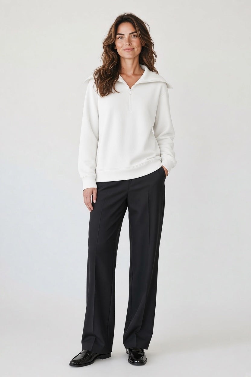 A person wearing a SAVE THE DUCK - HINATA HALF ZIP TOP IN CLOUD WHITE with a wide collar, paired with black trousers and black loafers for a modern silhouette.