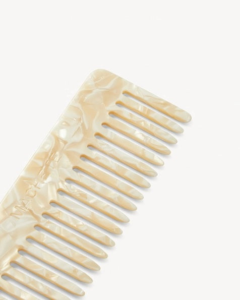 The MACHETE - No. 2 Comb in Ivory, crafted from marbled Italian acetate in a cream hue and featuring wide-set teeth, is displayed vertically against a plain white background.