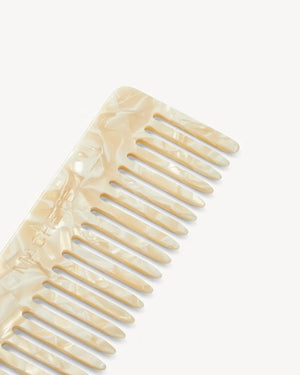 The MACHETE - No. 2 Comb in Ivory, crafted from marbled Italian acetate in a cream hue and featuring wide-set teeth, is displayed vertically against a plain white background.
