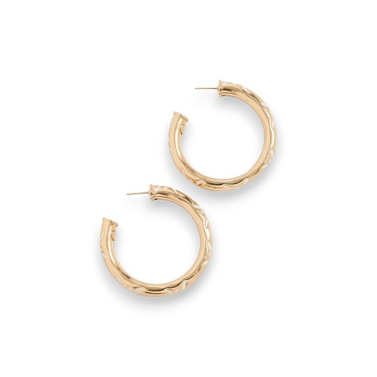 The GAS BIJOUX - BARI HOOP EARRINGS are medium-sized gold hoops featuring a subtle, textured pattern. Crafted from 24k gold, they boast a smooth, polished finish and secure latch-back closures. These exquisite earrings by GAS BIJOUX are presented on a plain white background.