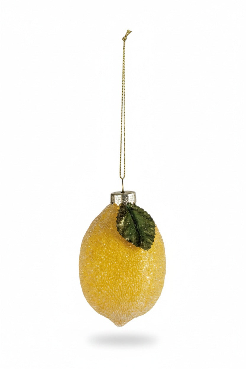 A Creative Coop hand painted glass lemon ornament with glitter, featuring a green leaf, beaded accents, and a gold hanging string.