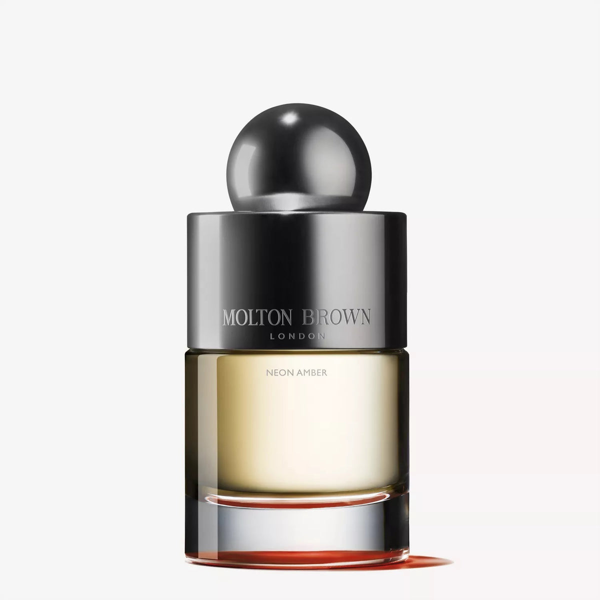 A 100 ml bottle of MOLTON BROWN - NEON AMBER EAU DE TOILETTE features a round metallic cap, silver collar, and clear glass displaying pale amber liquid, set against a plain light background.