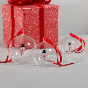 ZODAX SNOWMAN GLASS ORNAMENT: a clear 4-inch glass ball containing a small snowman figure, hung from a red ribbon.