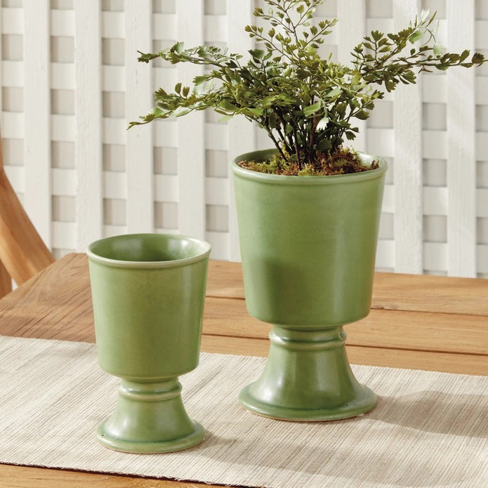 Two NAPA HOME AND GARDEN - KELCY FOOTED CACHEPOT planters, one taller than the other, with wide footed bases and a matte green ceramic finish, are displayed side by side on a plain white background.