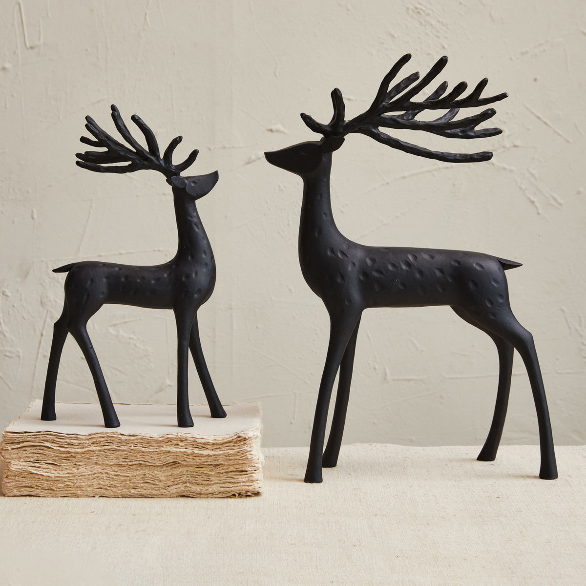 The CREATIVE COOP BLACK RESIN STANDING DEER features a minimalist large sculpture with long, stylized antlers and a textured surface, displayed against a plain white background.