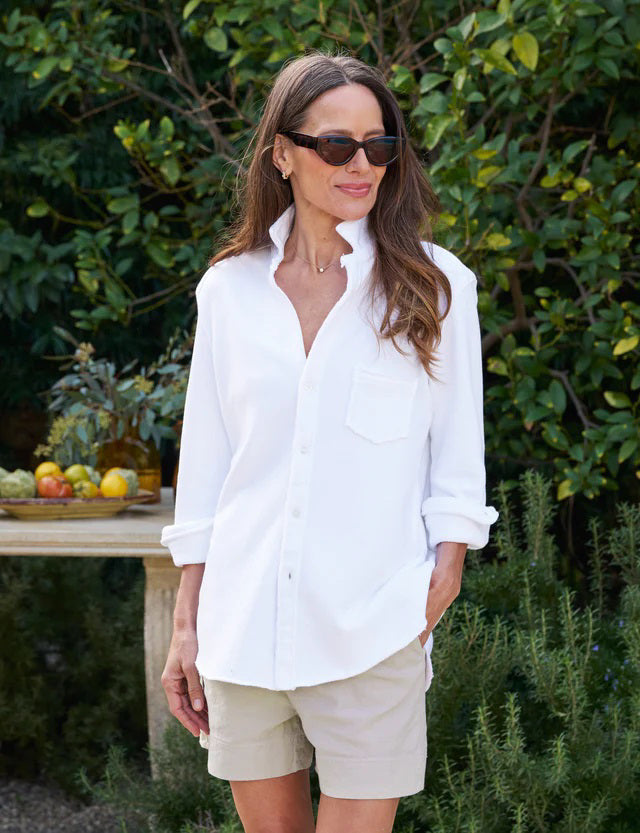 The FRANK AND EILEEN - EILEEN RELAXED BUTTON UP IN TRIPLE FLEECE WHITE features a collared neckline, buttons down the front, and a single chest pocket. The long sleeves are rolled up, and the inside collar label reads &quot;Frank &amp; Eileen EST 1947.&quot; With its relaxed fit and slightly curved hem, it exudes a casual, laid-back vibe.
