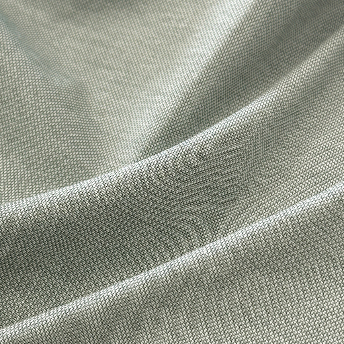 A man with short dark hair and a beard wears sunglasses and the COLLARS AND CO - PALM PIMA BLEND QUARTER ZIP IN MINT over a white collared shirt, leaning against a light-colored wall outdoors, showcasing modern comfort in this pullover.