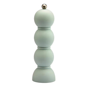 Green shelves showcase ADDISON ROSS LONDON's Scandi Bobbin Salt or Pepper Mill (23cm), a striped vase with white flowers, books, a bowl of red apples, and a vintage Campari poster in vivid green and red.
