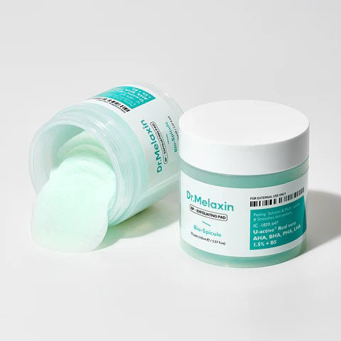 Two containers of DR MELAXIN - BP EXFOLIATING PADS from KOSMIC KBEAUTY SKINCARE are shown on a light surface—one open with mint-green pads partly pulled out, the other closed.