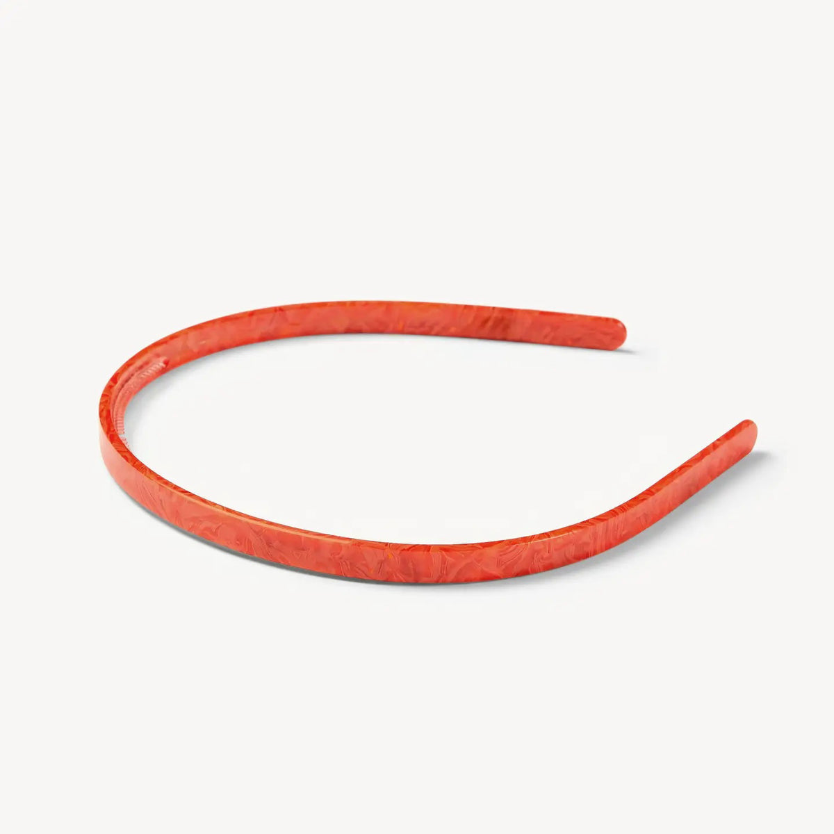 The MACHETE Ultralight Thin Headband in Poppy, crafted from Italian acetate in a vibrant marbled orange and hand-polished for a smooth finish, is shown against a plain white background.