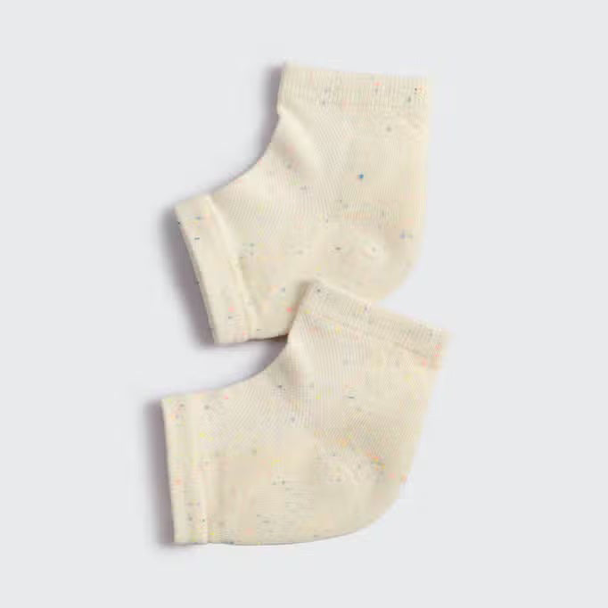 Displayed against a plain background are two light beige KITSCH - MOISTURIZING HEEL SOCKS with subtle multicolored speckles. They feature an insulated gel lining, positioned side by side to show their knit texture, promising to hydrate and soften your skin.