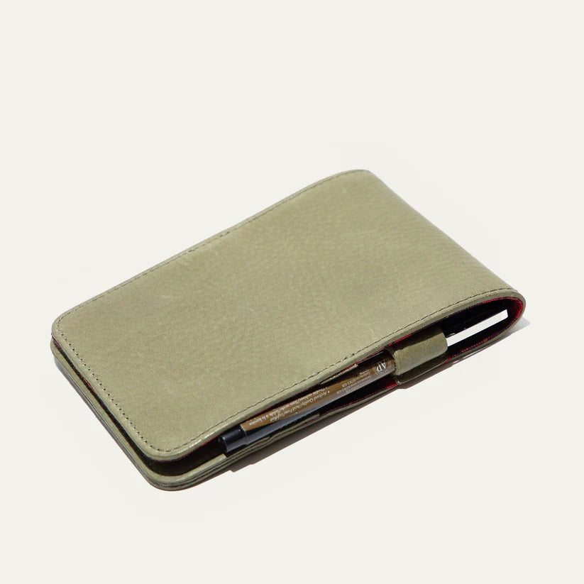 The WILL LEATHER GOODS - GOLF YARDAGE BOOK IN GREEN lies open with a black and brown pen in front, displayed on a plain white background.