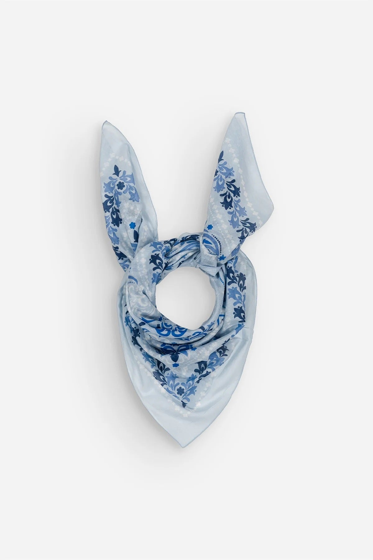 The MAISON LECOMTE - DINARD BANDANA SCARF IN COTTON VOILE by MAISON LECOMTE FLAMENT is a square, light blue cotton voile bandana adorned with an intricate paisley and floral pattern in shades of dark and light blue, elegantly displayed flat on a white background—an ideal accessory for any occasion.