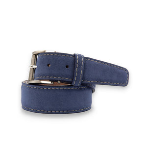 The LEN LIFESTYLE L.E.N. LIFESTYLE - ALCANTARA BELT IN BLUE JEAN features blue suede, white stitching, a silver buckle, and tan lining, displayed in a circular shape on a white background.