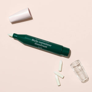 The MANICURIST - CORRECTOR PEN by MANUCURIST INC is a green and pink pen with a clear cap and white brush tip labeled “Stylo correcteur,” ideal for fixing nail polish or gel errors. Shown lying on a white background.