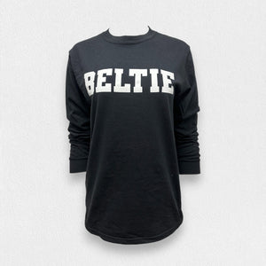 A black long sleeve tee shirt from the Fearrington Lifestyle Collection by Comfort Colors, crafted from premium fabric with the word "BELTIE" printed in large, bold, white capital letters on the front, neatly folded and laid on a white textured surface.