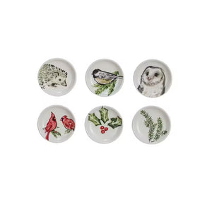 Six small, round Creative Coop stoneware dishes with hand-painted botanical animal illustrations of a hedgehog, owl, birds, or winter greenery.