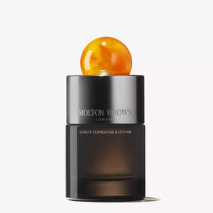 A sleek, dark MOLTON BROWN - SUNLIT CLEMENTINE & VETIVER AU DE PARFUM bottle with a marbled orange cap captures the citrus essence of this Eau de Parfum against a plain white background.