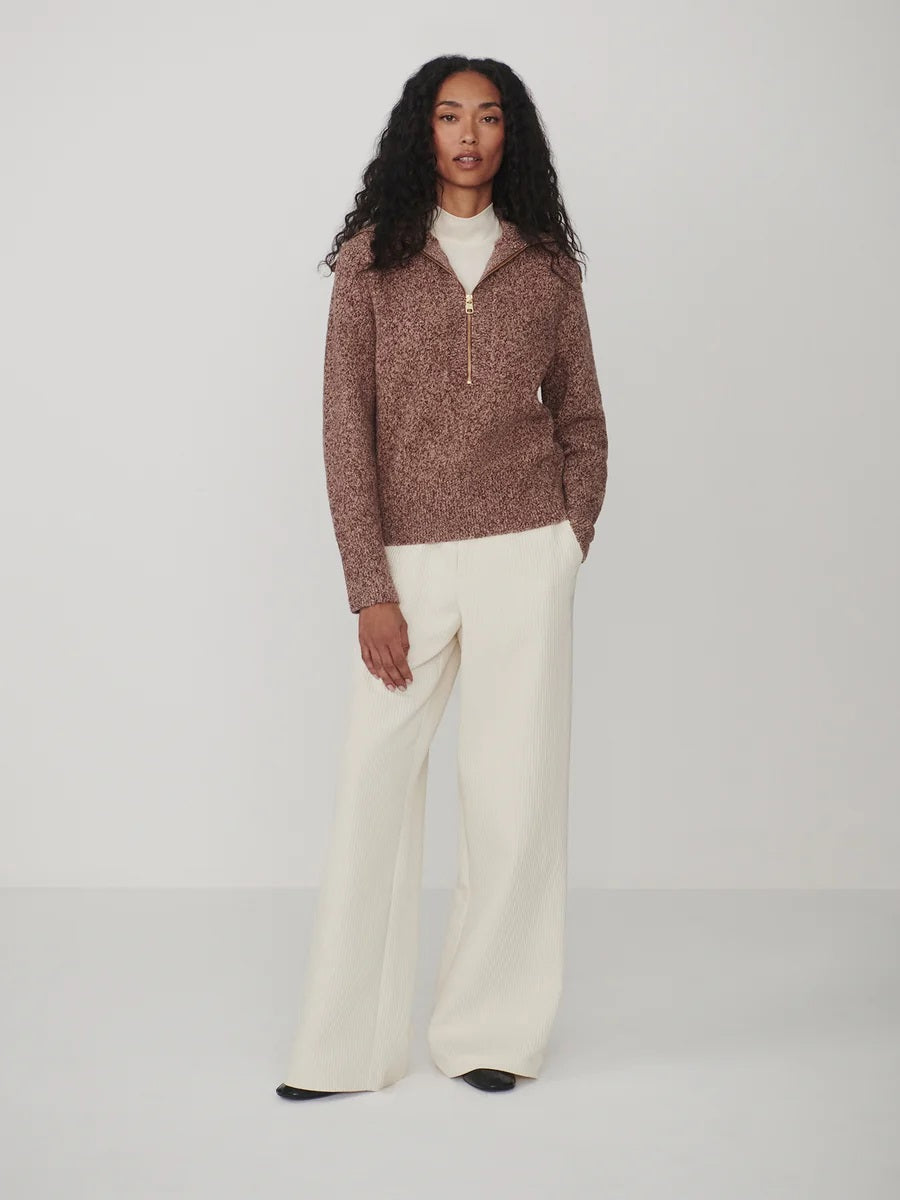 A person wearing a VARLEY - SHERIDA HALF-ZIP KNIT SWEATER IN GINGERBREAD FLECK, a brown speckled boucle yarn sweater with a collared half-zip neckline.